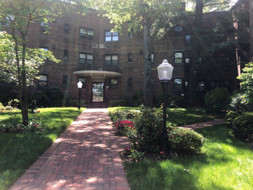 50 Brompton Road, Unit 1T Great Neck, NY 11021 - Photo 1 of 33 a front view of a house with a yard and a garden